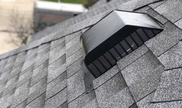 Low-profile black roof exhaust vent cap installed on gray asphalt shingles