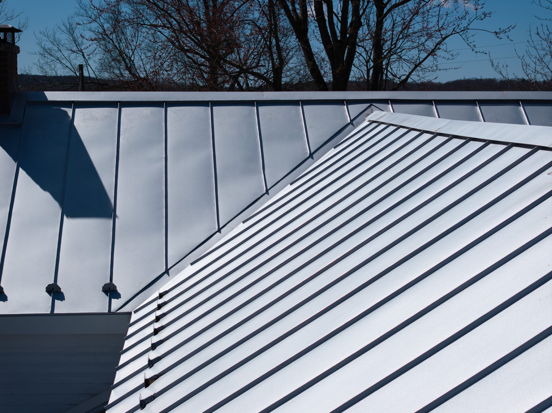 Dark standing seam metal roof panels with raised seams on a two-story home
